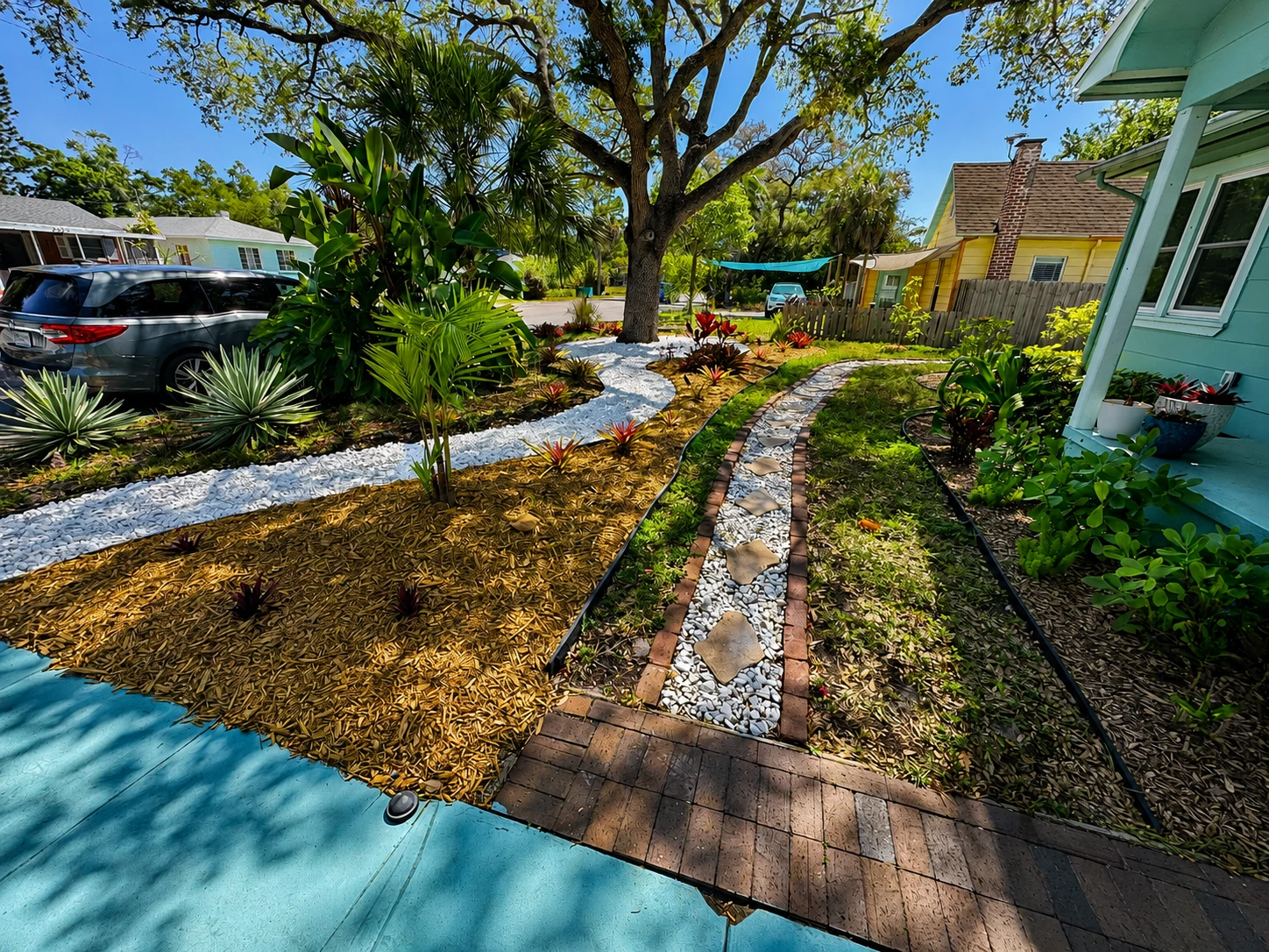 Finished Florida yard refresh with mulch, white rock, plants, and a bordered walkway.